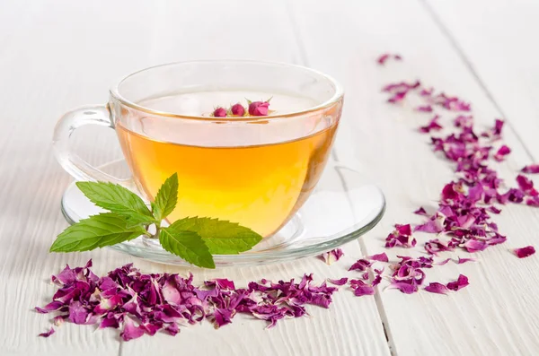 Steeg thee en gedroogde bloemblaadjes op witte houten tafel — Stockfoto