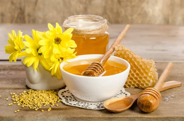 Yellow flowers and bee products (honey, pollen, honeycombs) on w — Stock Photo, Image