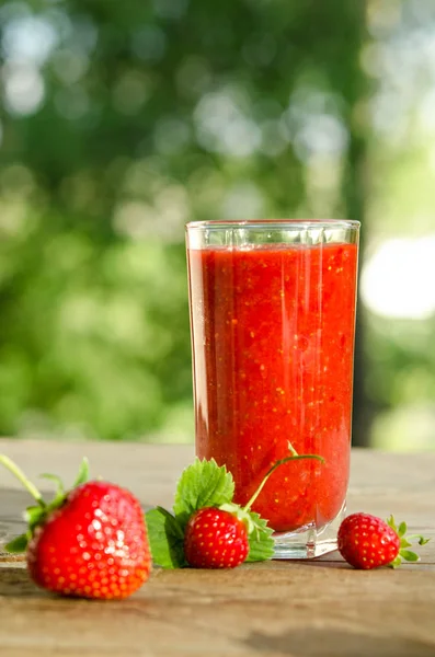 Strawberries and strawberry cocktail smoothie on a wooden table — Stock Photo, Image