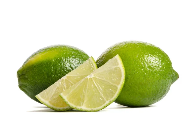 Två limefrukterna med skivor av saftig lime isolerad på vita bak — Stockfoto