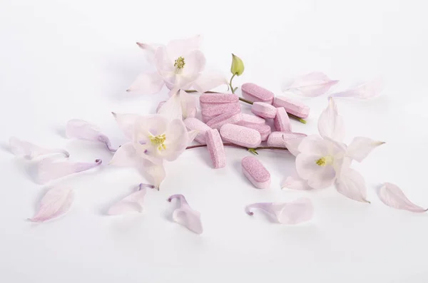 Comprimés de médecine alternative avec des fleurs et des pétales sur la table — Photo