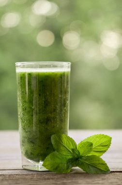  Yeşil smoothie ahşap bir masa ve nane yaprakları ile cam