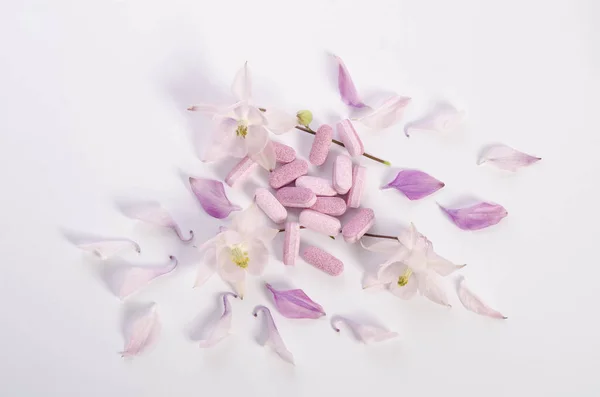 Tabletas de medicina alternativa con flores y pétalos en la mesa —  Fotos de Stock