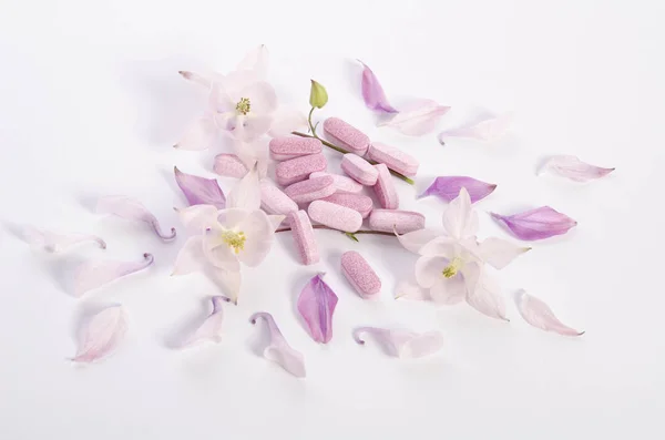 Tabletas de medicina alternativa con flores y pétalos en la mesa —  Fotos de Stock