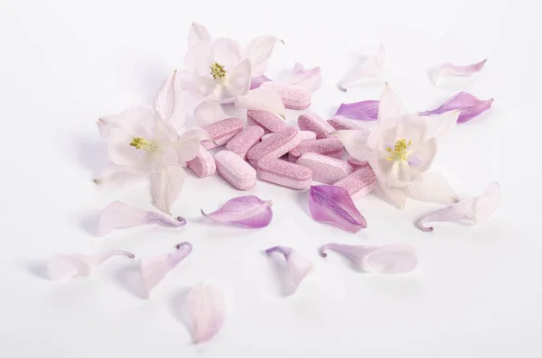 Comprimés de médecine alternative avec des fleurs et des pétales sur la table — Photo