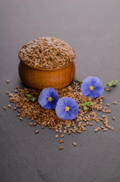 Semi di lino nella ciotola di legno, fiore di bellezza e olio in tappi su — Foto Stock