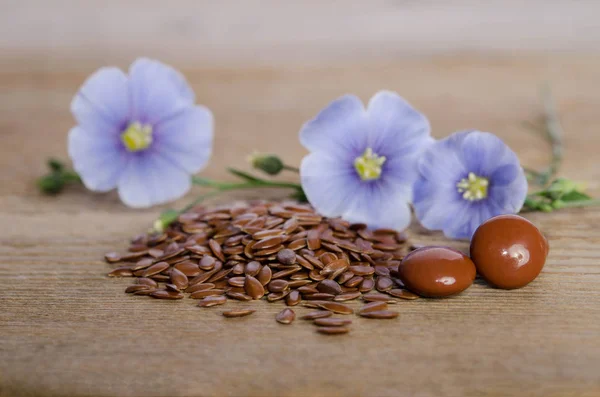 Semi di lino, fiore di bellezza e pillole su sfondo di legno. Fito — Foto Stock