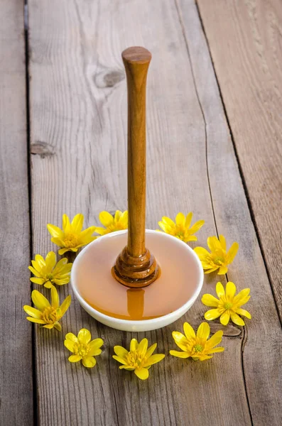 Miel en el cuenco de vidrio, cazo y flores amarillas a su alrededor — Foto de Stock