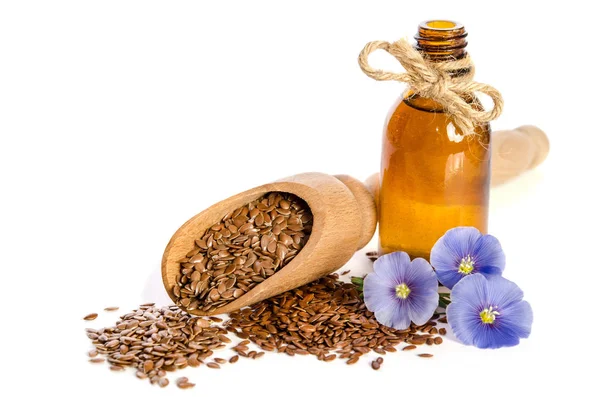 Sementes de linho em colher de madeira, garrafa com flores de óleo e beleza — Fotografia de Stock