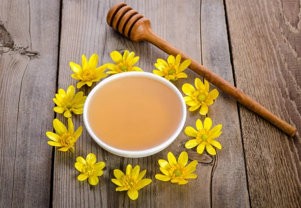 Мед в стеклянной чаше и желтые цветы вокруг него — стоковое фото