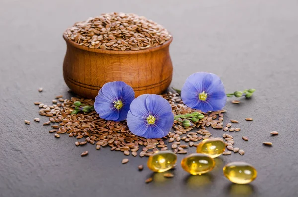 Semi di lino nella ciotola di legno, fiore di bellezza e olio in tappi — Foto Stock