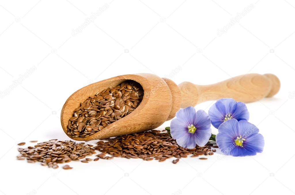 Flax seeds in the wooden scoop and  beauty flowers