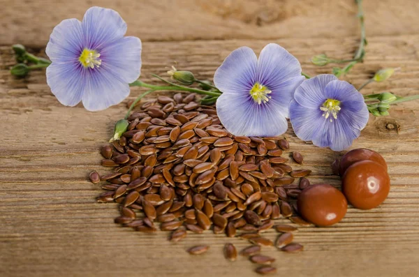 Flax seeds , beauty flower and pills on woooden background — Stock Photo, Image