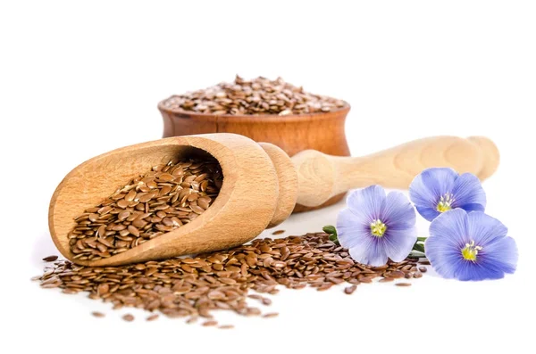 Flax seeds in the wooden bowl, wooden scoop and beauty flowers — Stock Photo, Image
