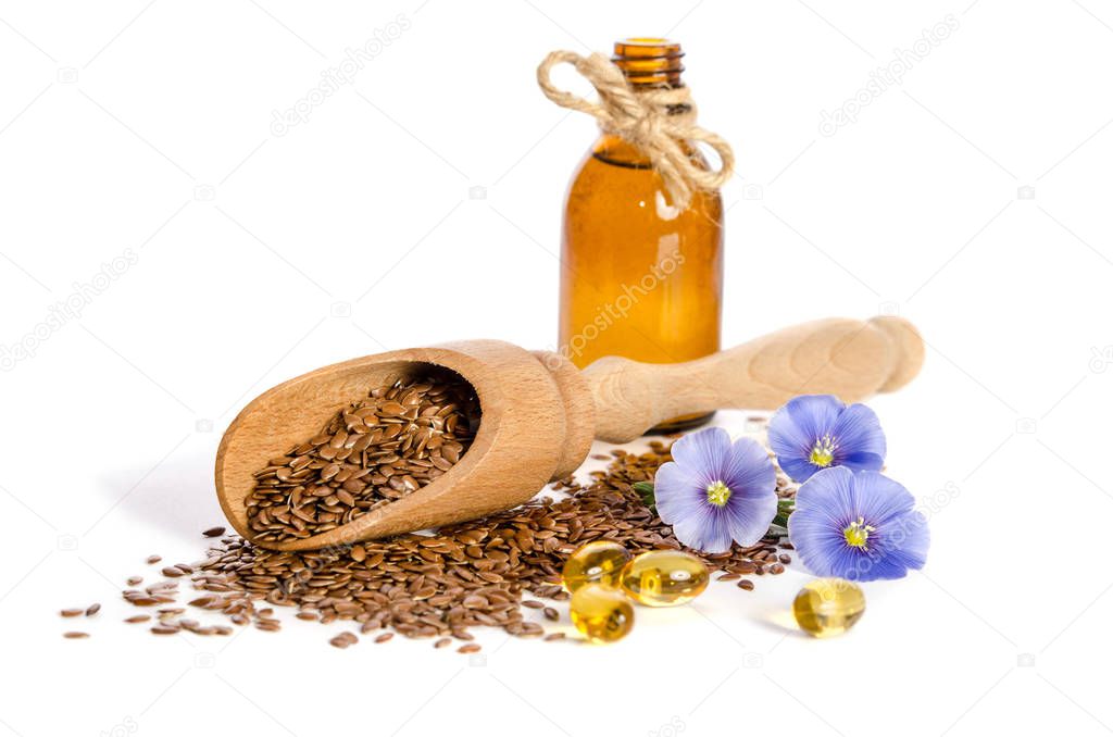 Flax seeds in the wooden scoop, bottle with oil and  beauty flowers