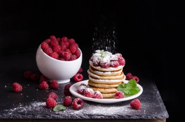 Kase ve siyah artalan üzerinde ahududu ile Pancakes