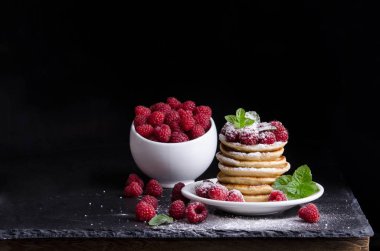 Kase ve siyah artalan üzerinde ahududu ile Pancakes