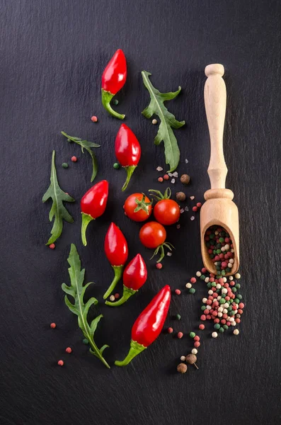 Verschiedene Gewürze mit Tomate und Paprika auf schwarzem Hintergrund — Stockfoto