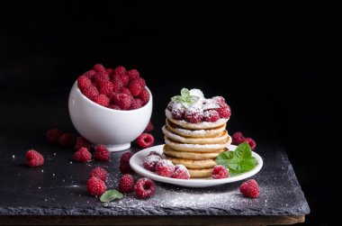 Kase ve siyah artalan üzerinde ahududu ile Pancakes