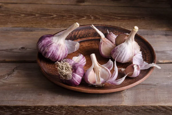 Garlic in the plate on old wooden table ( background ) — Stock Photo, Image