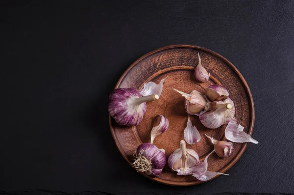 Garlic in the plate on black stone table / top view/ — Stock Photo, Image