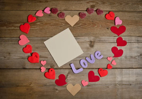 Word Love composition on the wooden board surface and many hearts — Stock Photo, Image