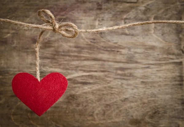 Corazón de tela roja colgando en el tendedero. Sobre fondo de madera vieja — Foto de Stock