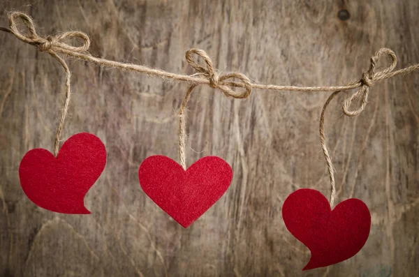 Três corações de tecido vermelho pendurados no varal — Fotografia de Stock