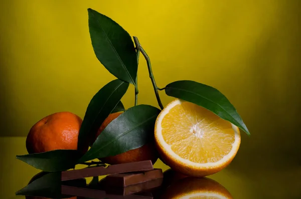 Oranges and Chocolate on dark yellow background — Stock Photo, Image