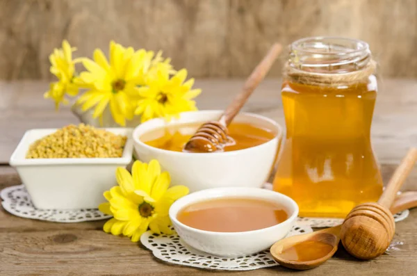 Желтые цветы и пчелиные продукты (мед, пыльца) на деревянном фоне — стоковое фото