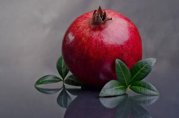 Ripe pomegranates with leaves  on a dark background. — Stock Photo, Image