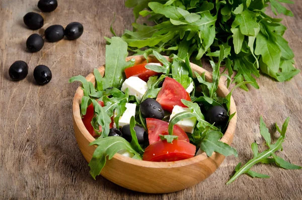 Salát s rajčaty a olivami na dřevěné pozadí. — Stock fotografie
