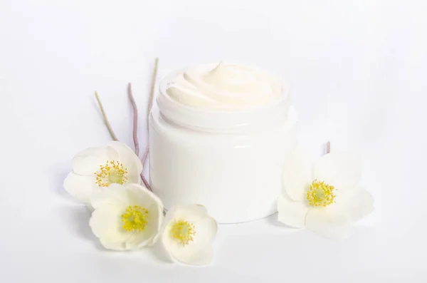 Cute flowers and a jar of natural body cream isolated on white