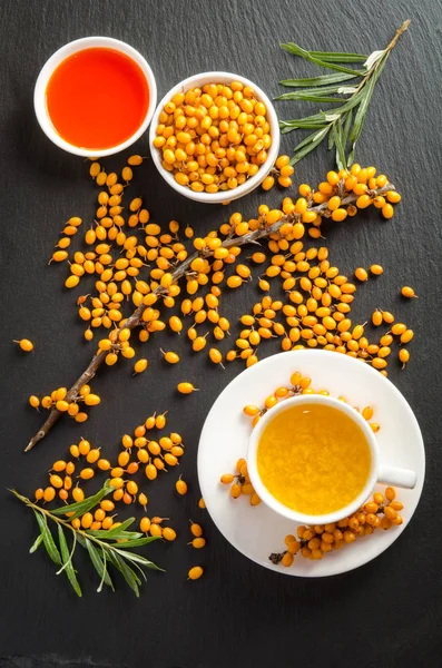 Cup of tea with sea buckthorn and bowl with sea buckthorn oil — Stock Photo, Image