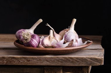  plaka eski ahşap masa ve siyah arka plan üzerine sarımsak