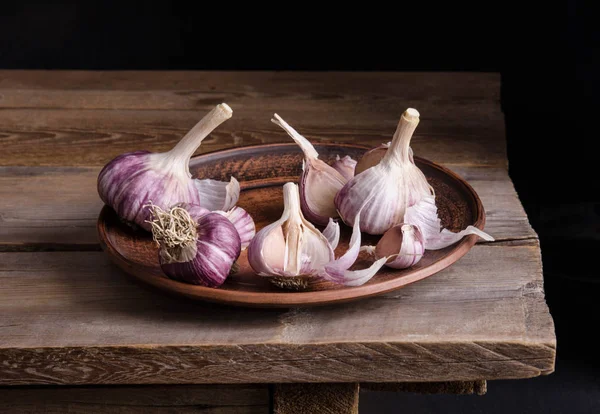 Garlic in the plate on old wooden table  and black background — Stock Photo, Image