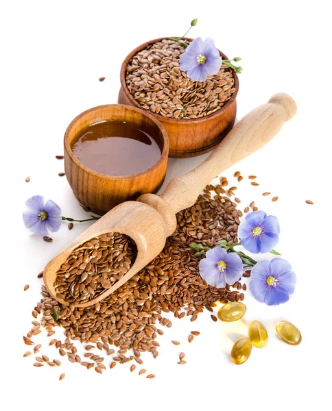 Flax seeds in the wooden scoop, bowl with oil and oil in caps — Stock Photo, Image