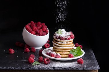 Kase ve siyah artalan üzerinde ahududu ile Pancakes