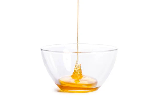 Despejar mel em uma tigela de vidro em um fundo branco — Fotografia de Stock