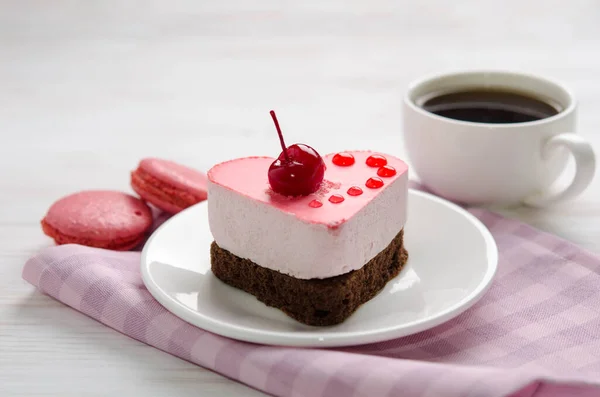 Souffle cake in the shape of heart  with cup of coffe and macaroons on a wooden table — Stock Photo, Image