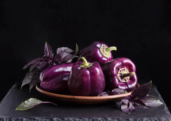 新鲜蔬菜 黑色背景的黑色石桌上放有罗勒叶的深色紫色辣椒 — 图库照片