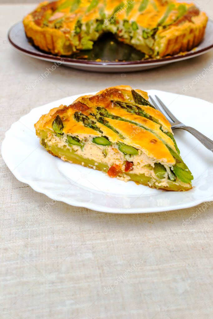Sliced slice of tart with green asparagus and toasted cheese on the table