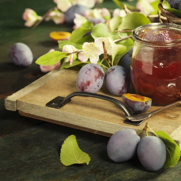 Švestky a sklenice džemu na stole — Stock fotografie