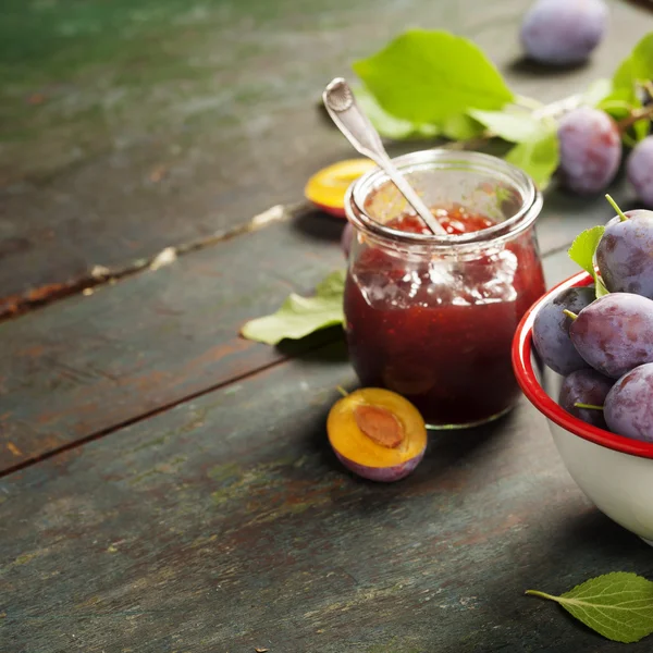 Plums and jar of jam on table — Stock Photo, Image