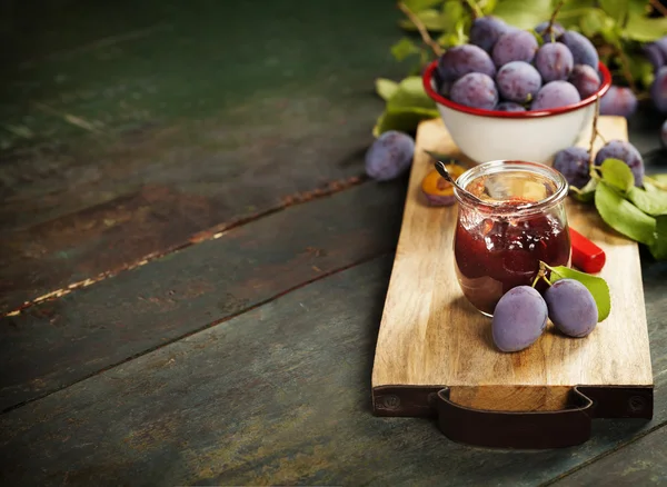 Plums and jar of jam on table — Stock Photo, Image