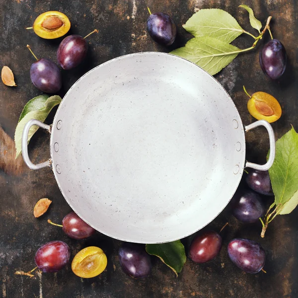 Old bowl and plums on a rural background — Stock Photo, Image
