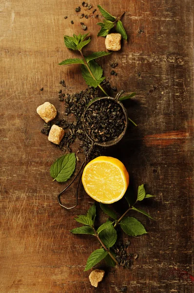 Dry tea with mint and lemon on wooden table — Stock Photo, Image