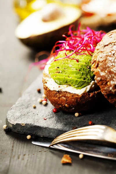 Sandwich de aguacate sobre pan de centeno oscuro hecho con aguacate fresco en rodajas —  Fotos de Stock