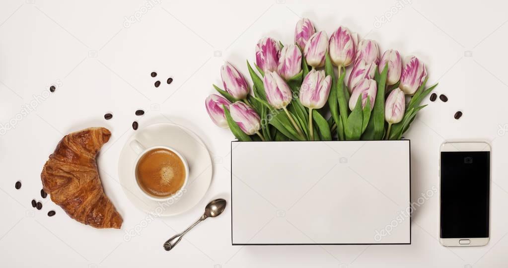Top view of spring flowers, coffee, mobile phone and cosmetics