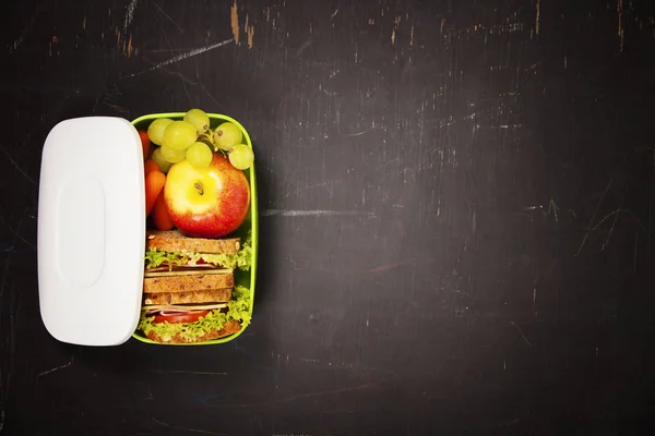 Green school lunch box with sandwich, apple, grape and carrot — Stock Photo, Image